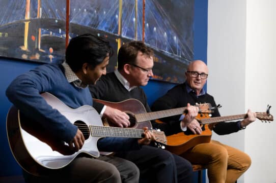 attorneys Roy Fernandes, Pat Reece, and Jim Dwyer play their accoustic guitars